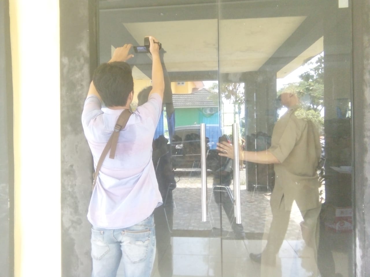 Salah seorang jurnalis mengambil gambar dari luar gedung DPPKAD Bengkulu Selatan, lantaran dilarang meliput oleh Plt. Bupati BS